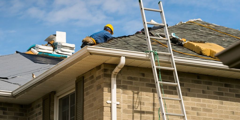 Roof worker installing new shingles on a roof of a house